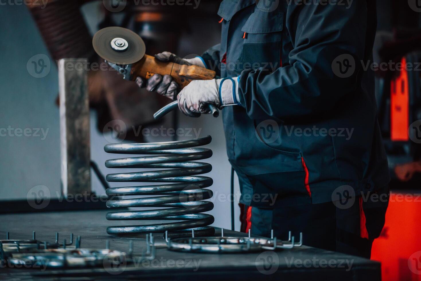 Locksmith in special clothes and goggles works in production. Metal processing with angle grinder. Sparks in metalworking. photo