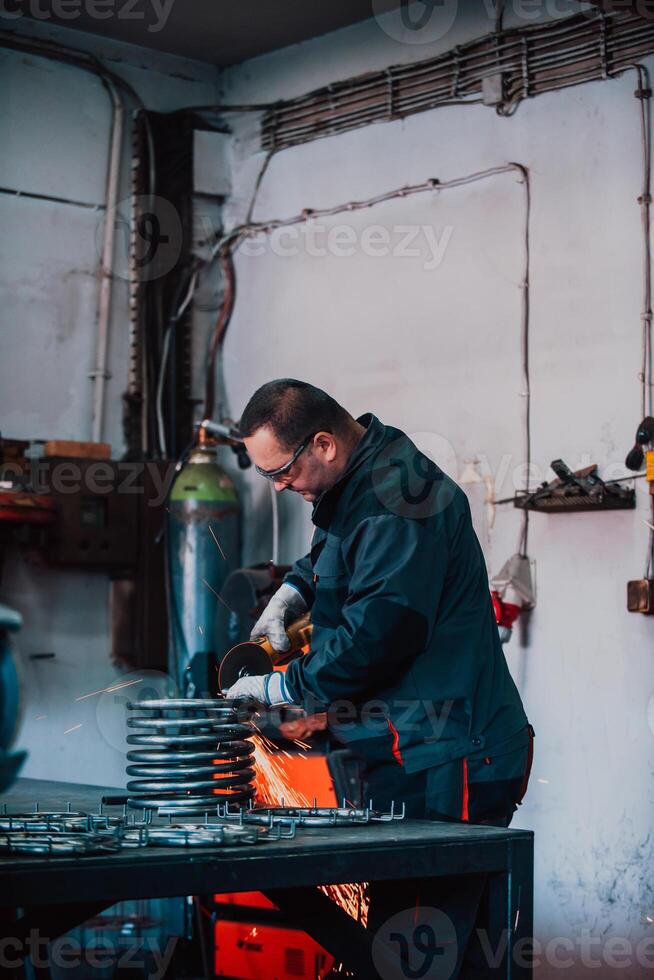 Locksmith in special clothes and goggles works in production. Metal processing with angle grinder. Sparks in metalworking. photo