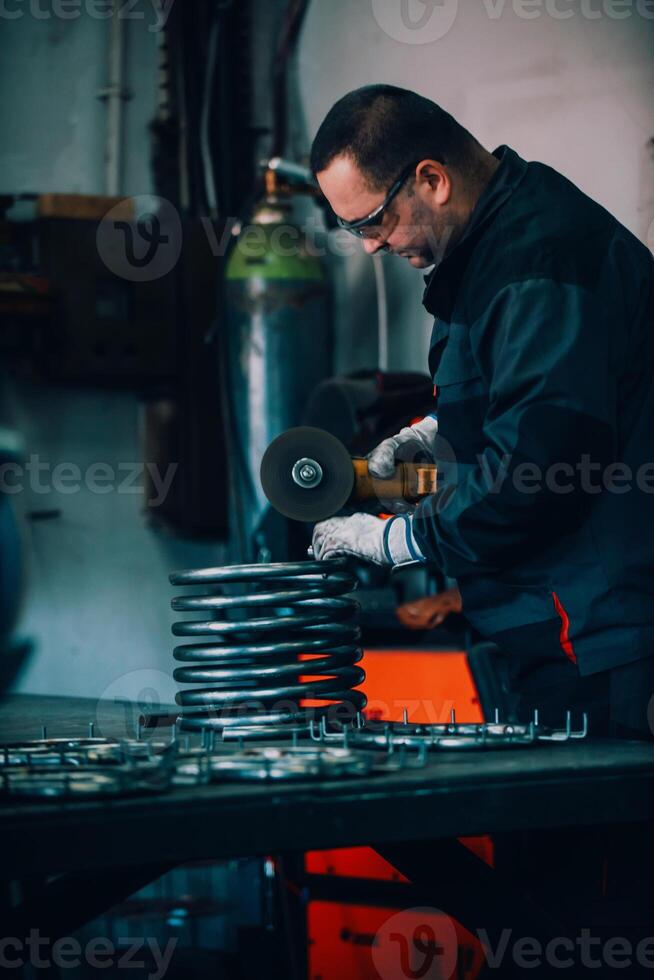 Locksmith in special clothes and goggles works in production. Metal processing with angle grinder. Sparks in metalworking. photo