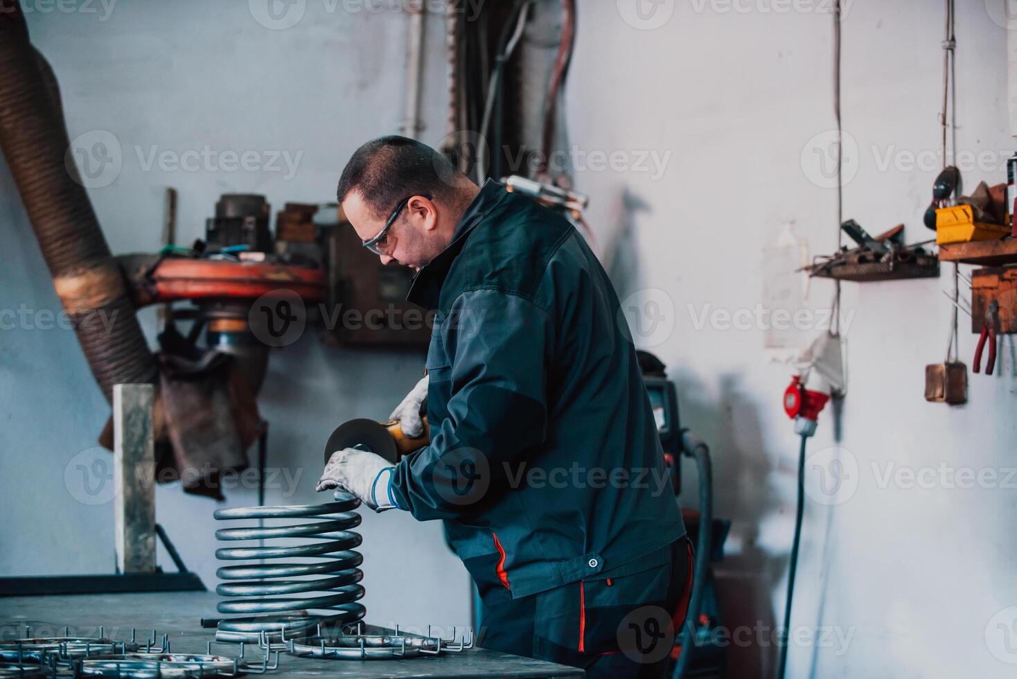 Locksmith in special clothes and goggles works in production. Metal processing with angle grinder. Sparks in metalworking. photo