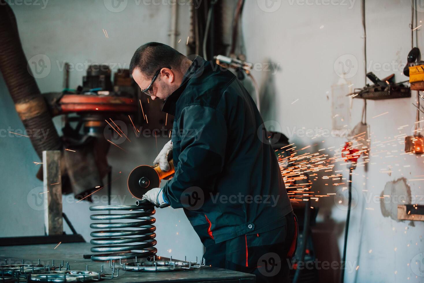 Locksmith in special clothes and goggles works in production. Metal processing with angle grinder. Sparks in metalworking. photo