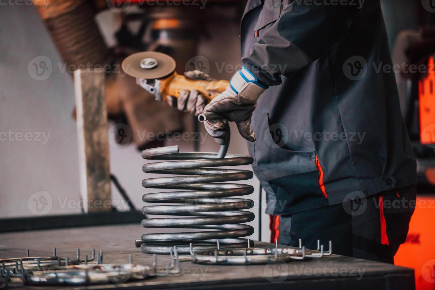 Locksmith in special clothes and goggles works in production. Metal processing with angle grinder. Sparks in metalworking. photo