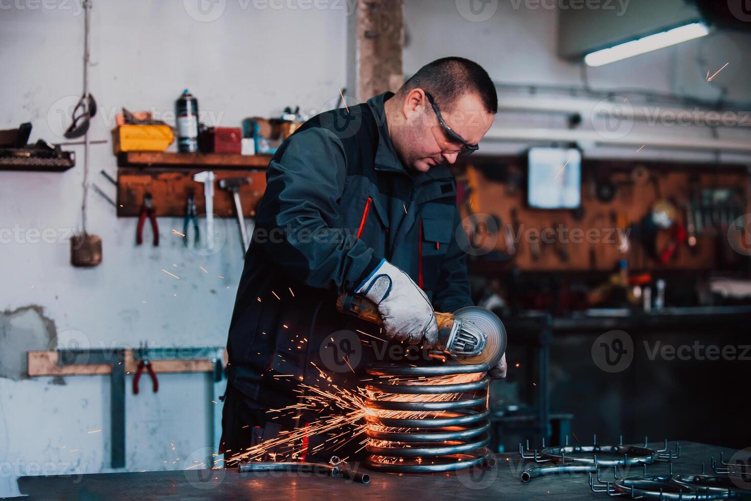 Locksmith in special clothes and goggles works in production. Metal processing with angle grinder. Sparks in metalworking. photo