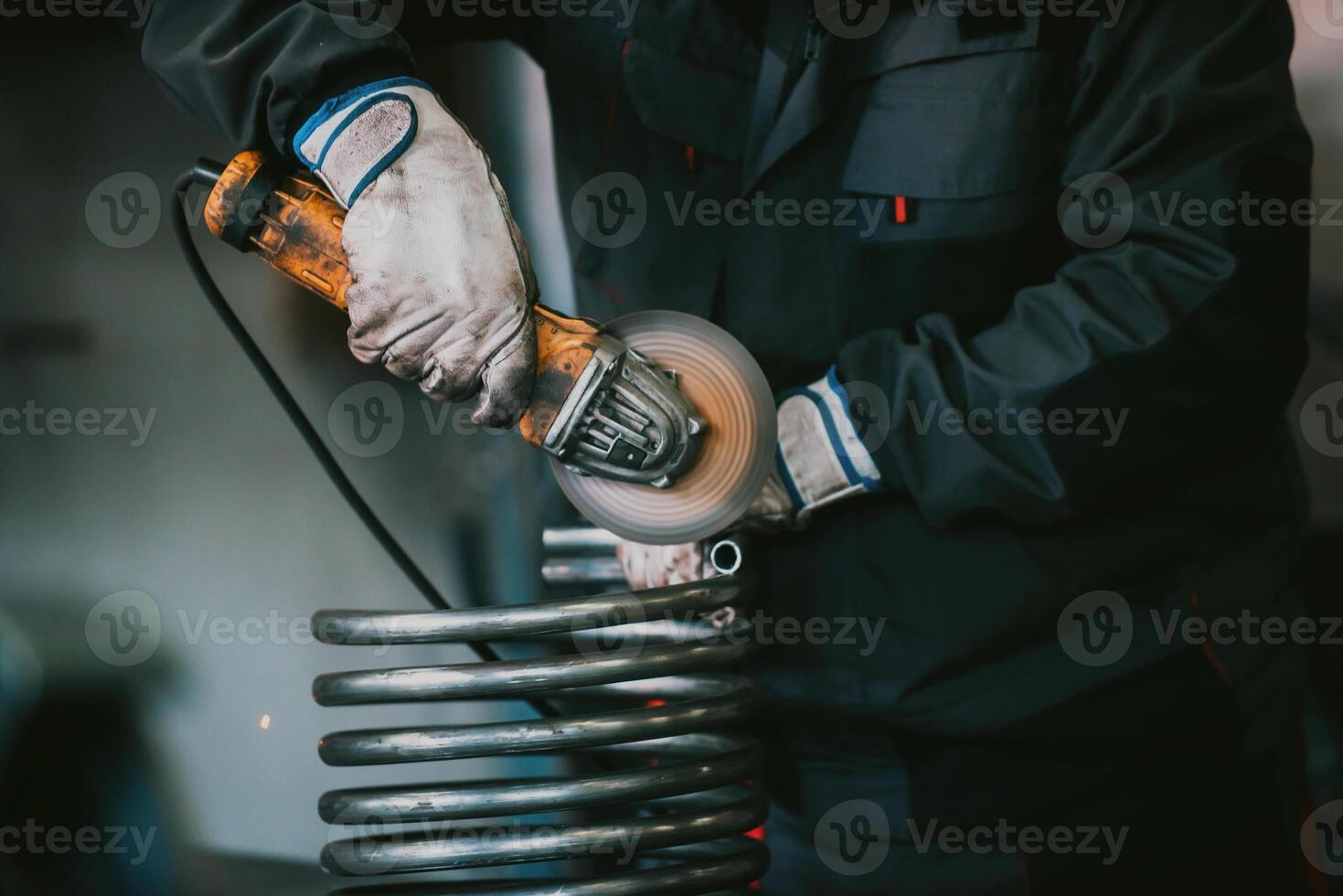 Locksmith in special clothes and goggles works in production. Metal processing with angle grinder. Sparks in metalworking. photo