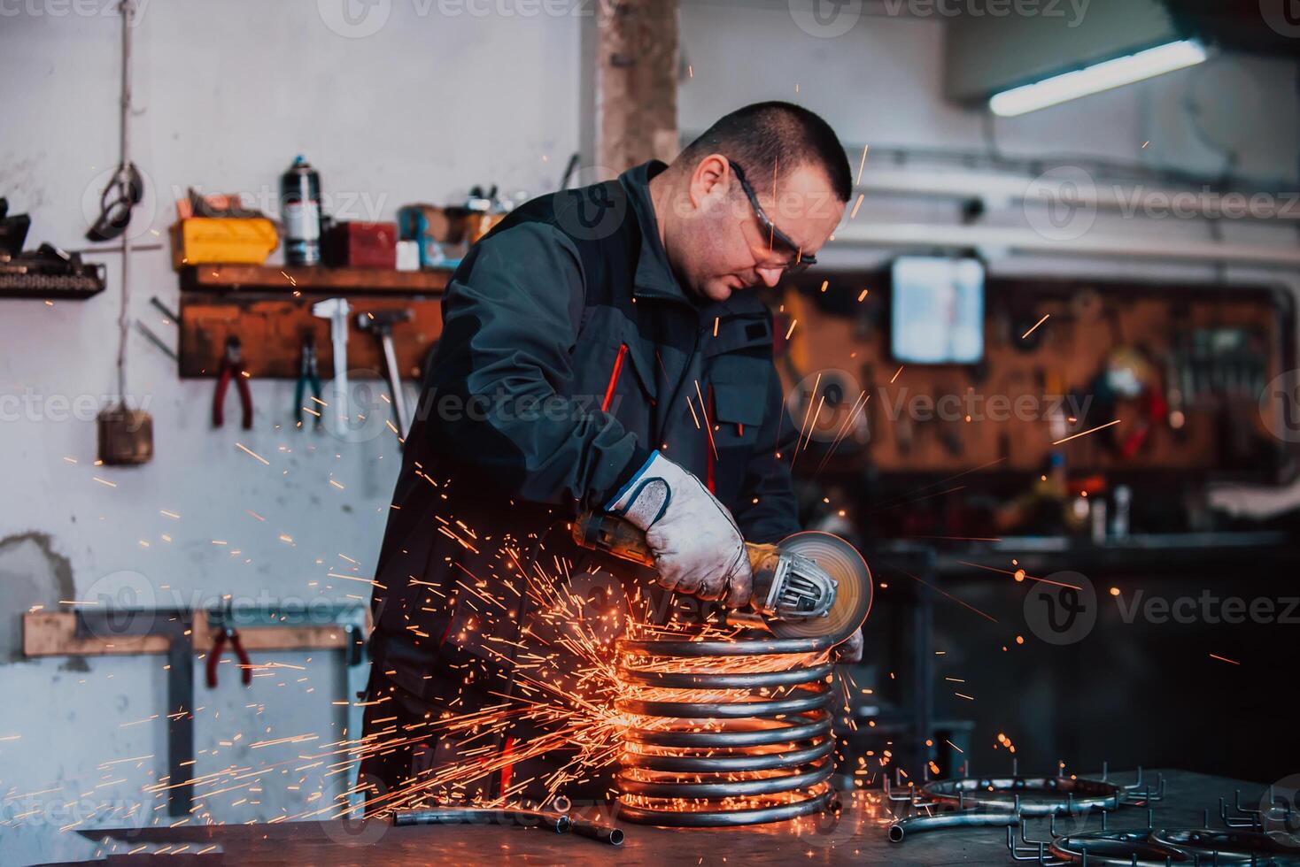 Locksmith in special clothes and goggles works in production. Metal processing with angle grinder. Sparks in metalworking. photo