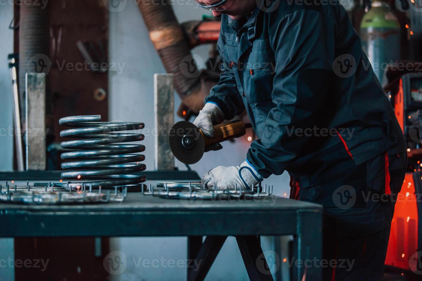 Locksmith in special clothes and goggles works in production. Metal processing with angle grinder. Sparks in metalworking. photo