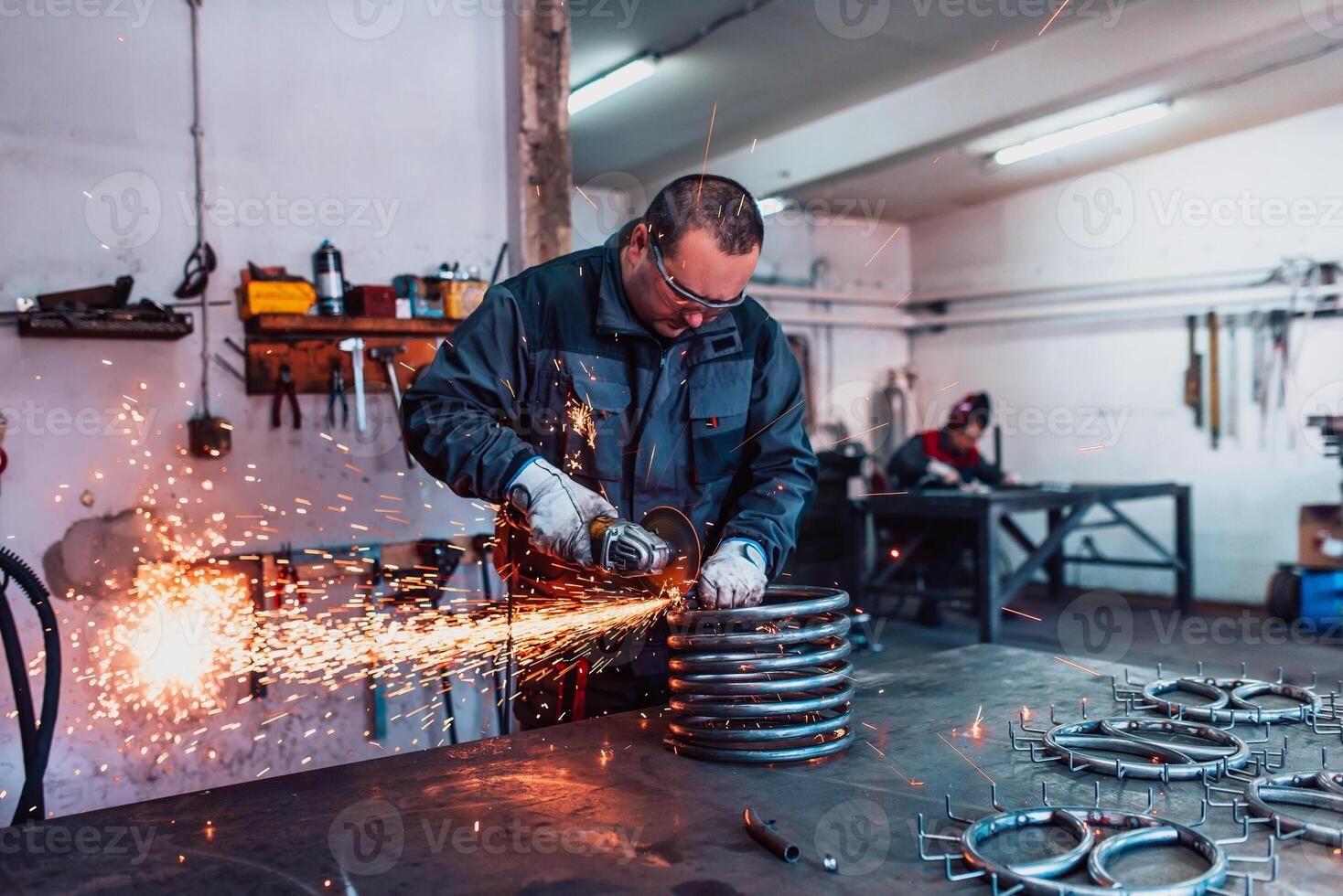 Locksmith in special clothes and goggles works in production. Metal processing with angle grinder. Sparks in metalworking. photo