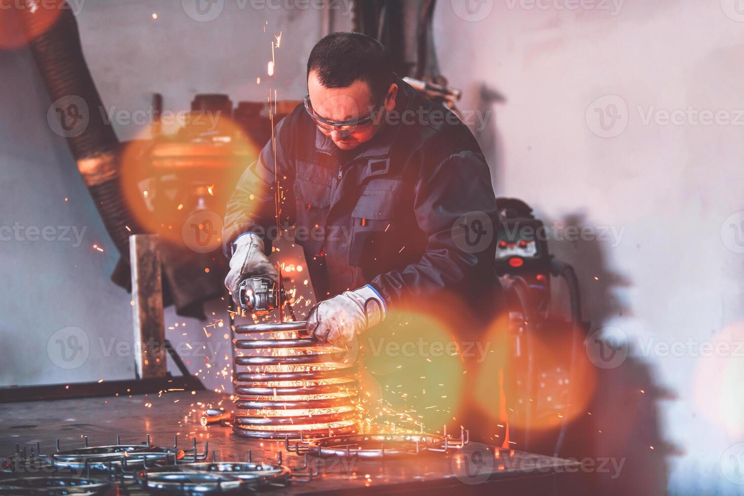 Locksmith in special clothes and goggles works in production. Metal processing with angle grinder. Sparks in metalworking. photo