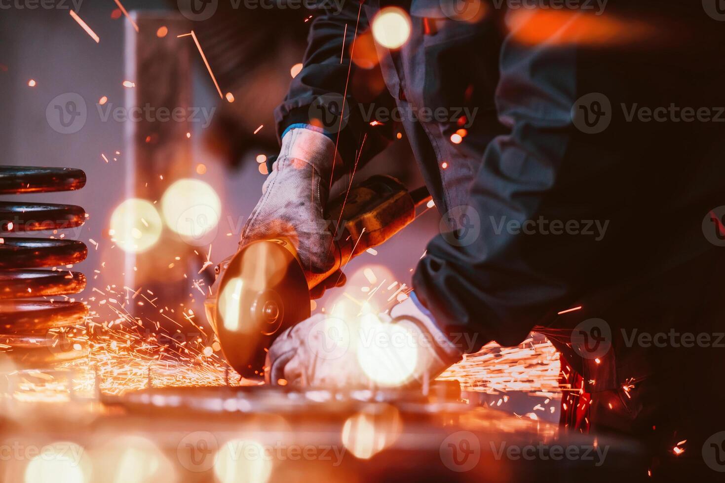 Locksmith in special clothes and goggles works in production. Metal processing with angle grinder. Sparks in metalworking. photo