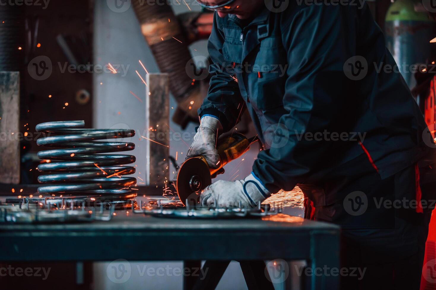 Locksmith in special clothes and goggles works in production. Metal processing with angle grinder. Sparks in metalworking. photo