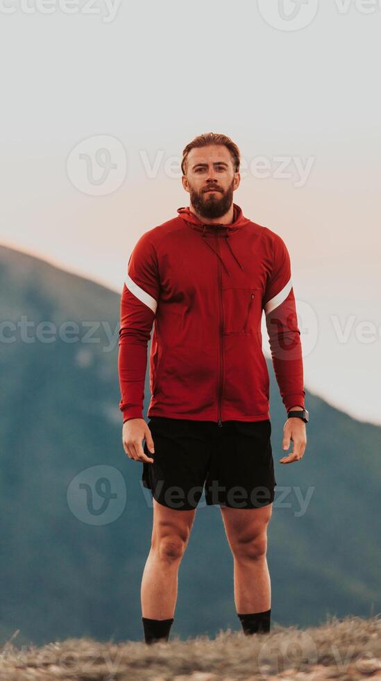 An athlete rests on top of a mountain after exhausting running training. photo