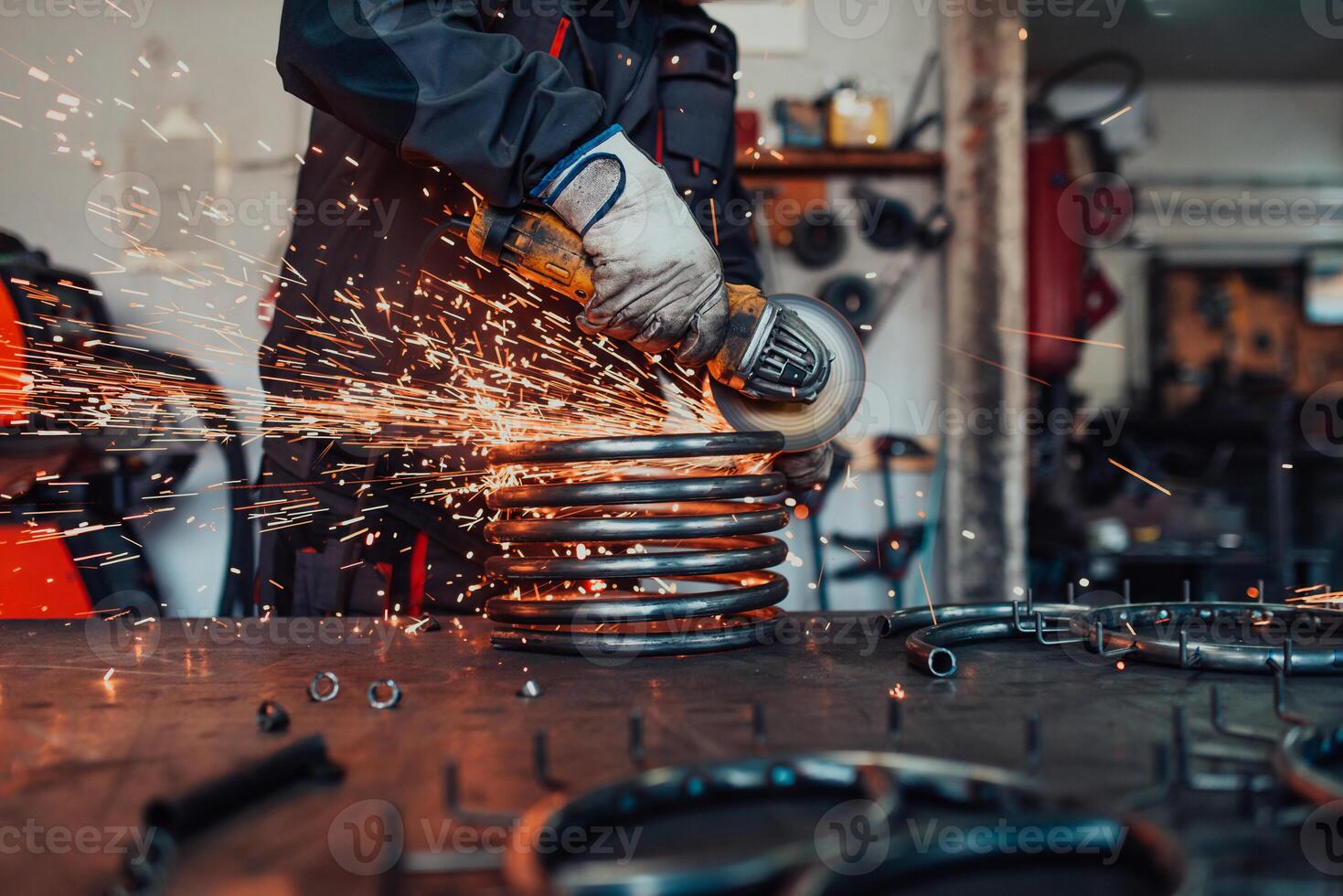 Locksmith in special clothes and goggles works in production. Metal processing with angle grinder. Sparks in metalworking. photo