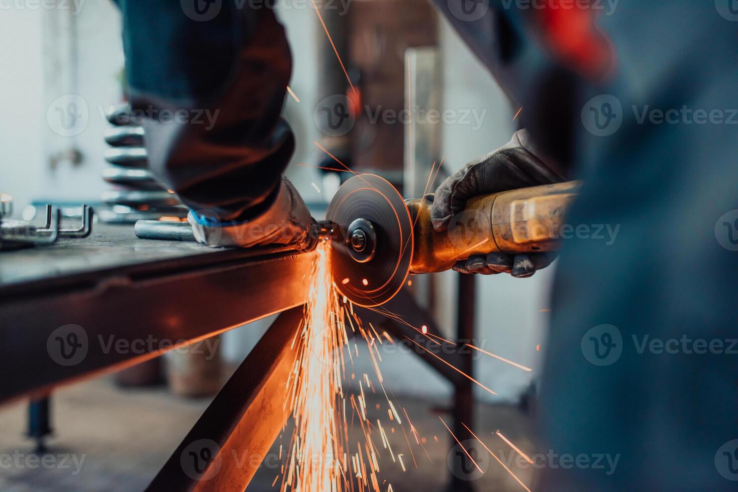 Locksmith in special clothes and goggles works in production. Metal processing with angle grinder. Sparks in metalworking. photo