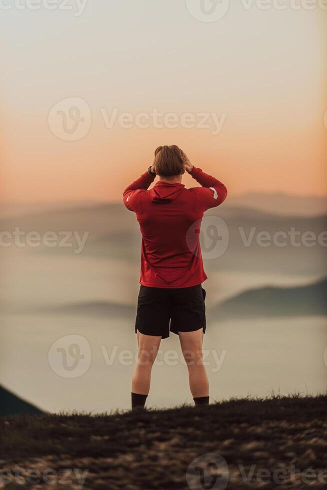 An athlete rests on top of a mountain after exhausting running training. photo