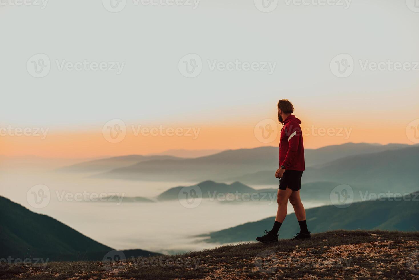 An athlete rests on top of a mountain after exhausting running training. photo