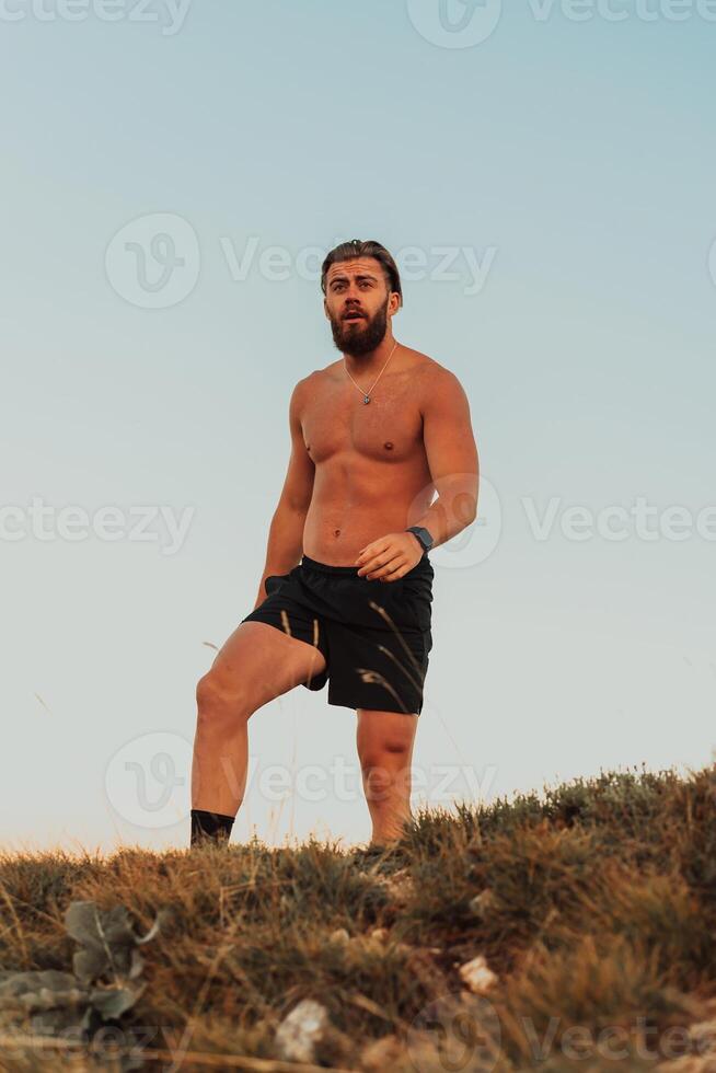 An athlete rests on top of a mountain after exhausting running training. photo
