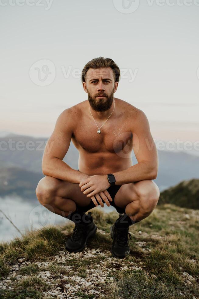 An athlete rests on top of a mountain after exhausting running training. photo