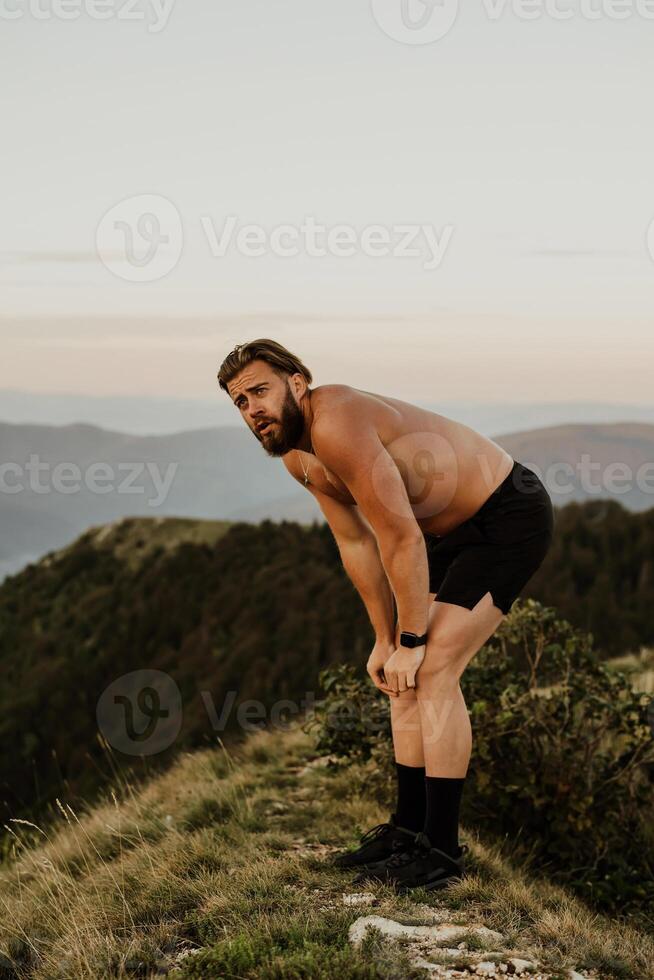 An athlete rests on top of a mountain after exhausting running training. photo