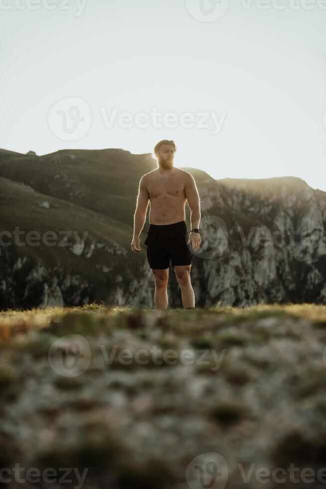 An athlete rests on top of a mountain after exhausting running training. photo