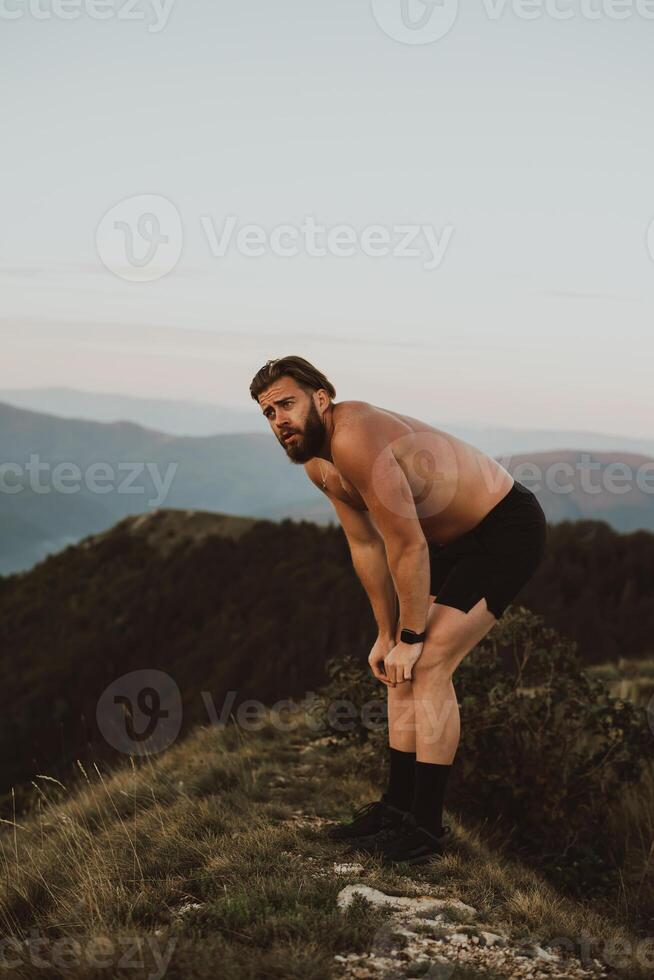 An athlete rests on top of a mountain after exhausting running training. photo