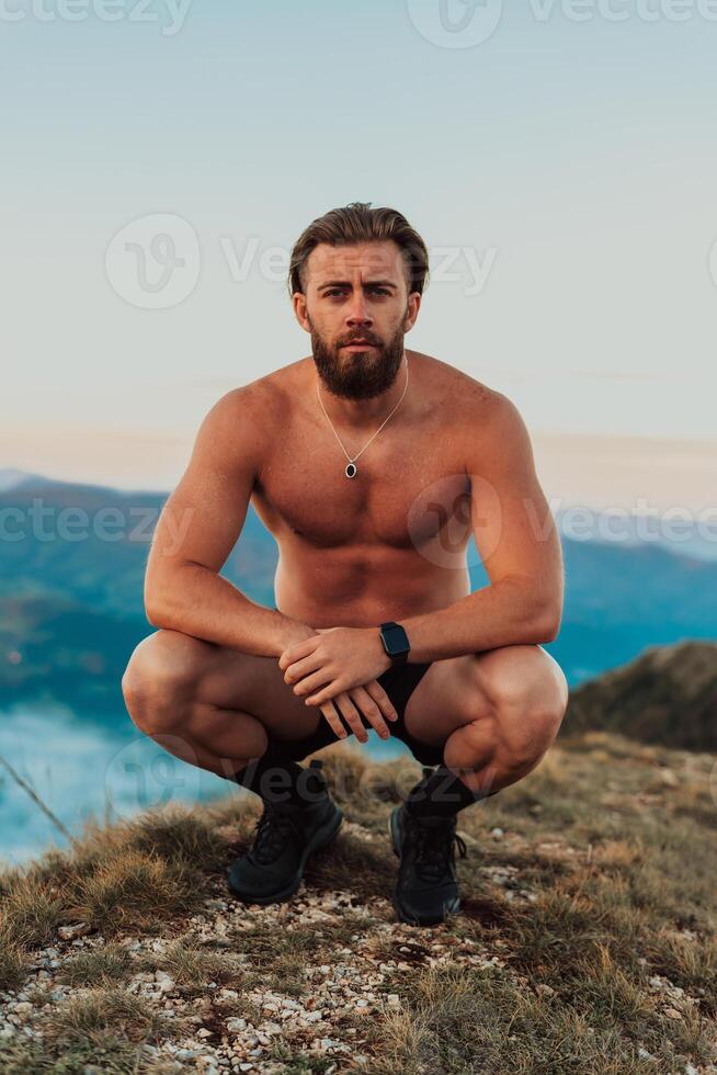 An athlete rests on top of a mountain after exhausting running training. photo