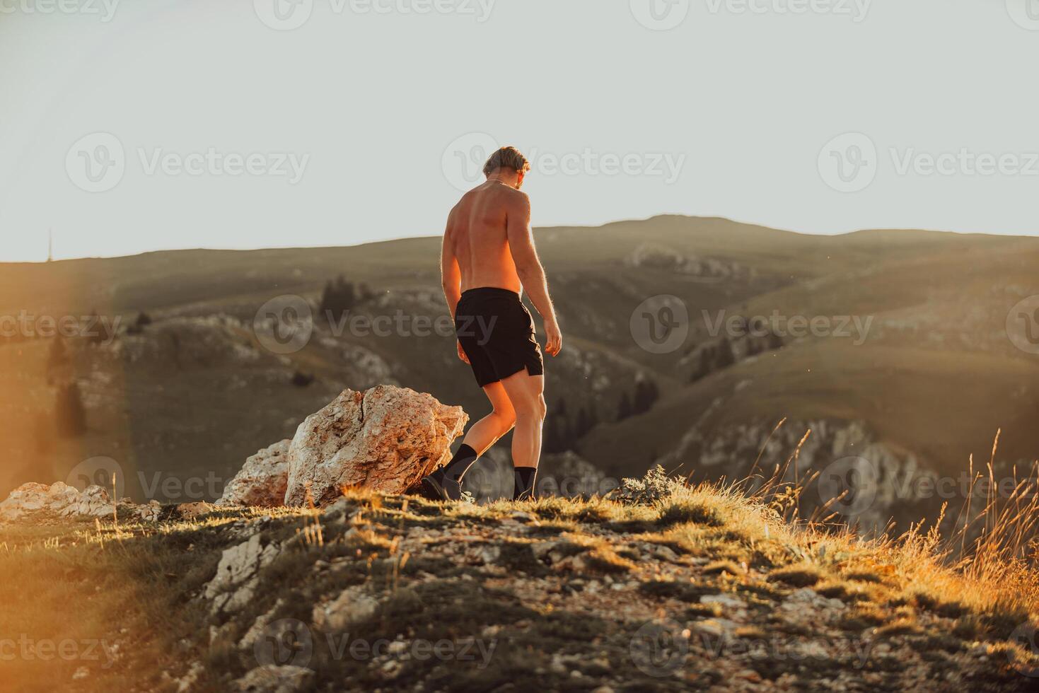 An athlete rests on top of a mountain after exhausting running training. photo