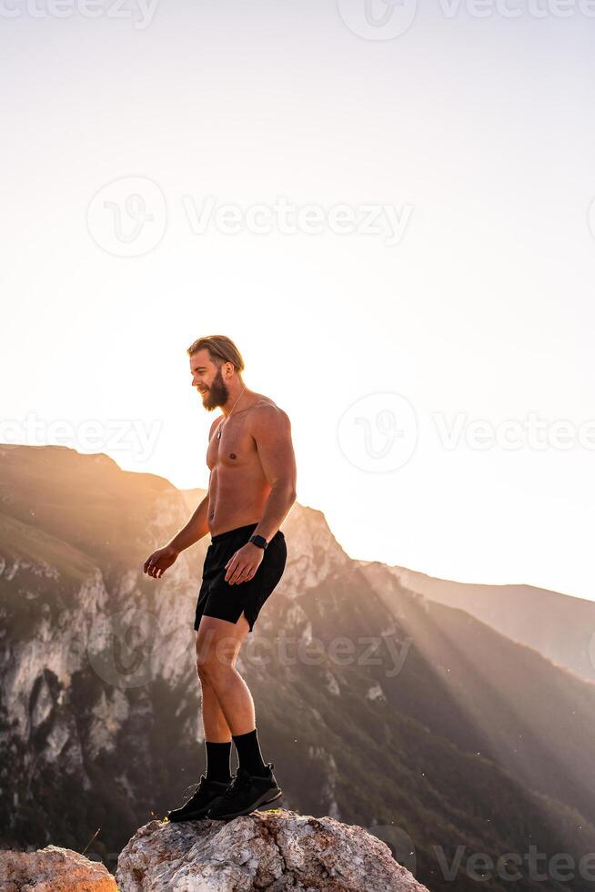 An athlete rests on top of a mountain after exhausting running training. photo