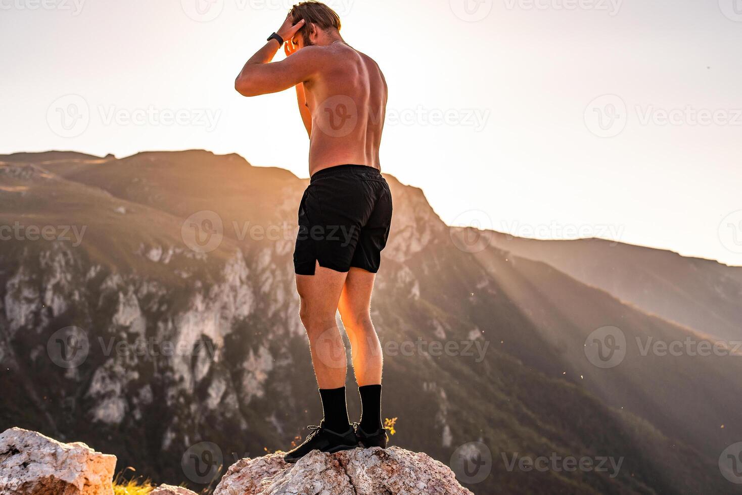 An athlete rests on top of a mountain after exhausting running training. photo