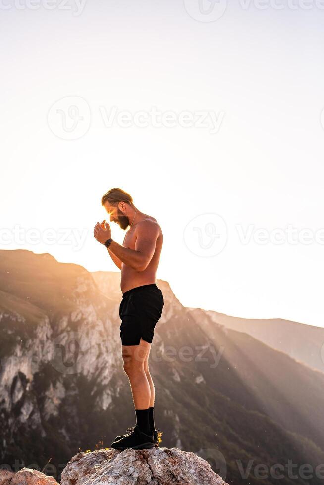 An athlete rests on top of a mountain after exhausting running training. photo