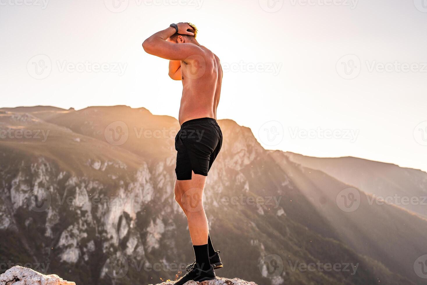 An athlete rests on top of a mountain after exhausting running training. photo