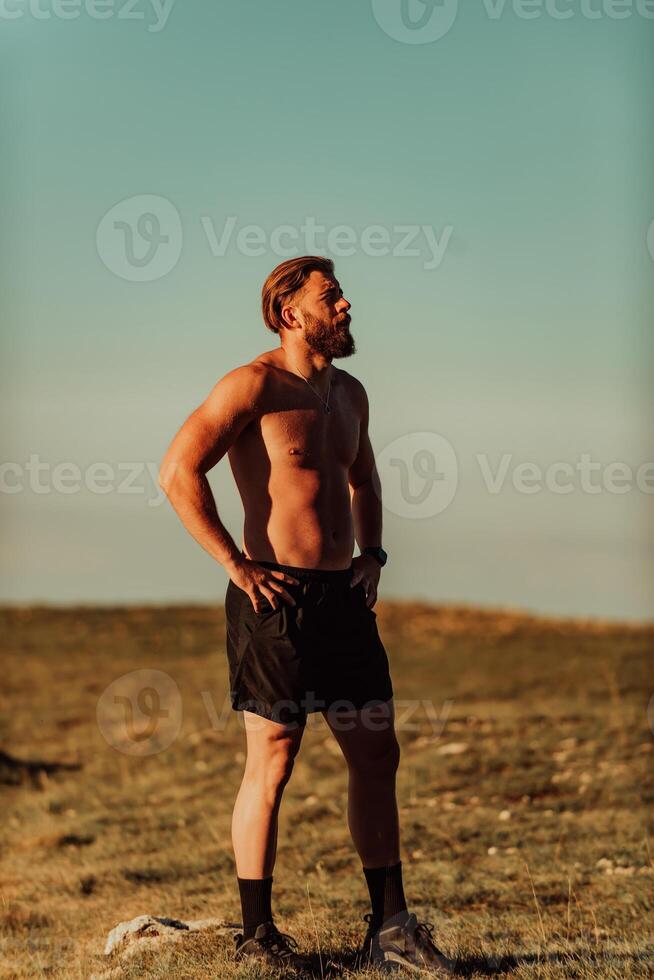 An athlete rests on top of a mountain after exhausting running training. photo