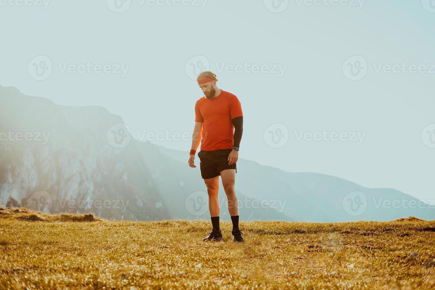 An athlete rests on top of a mountain after exhausting running training. photo