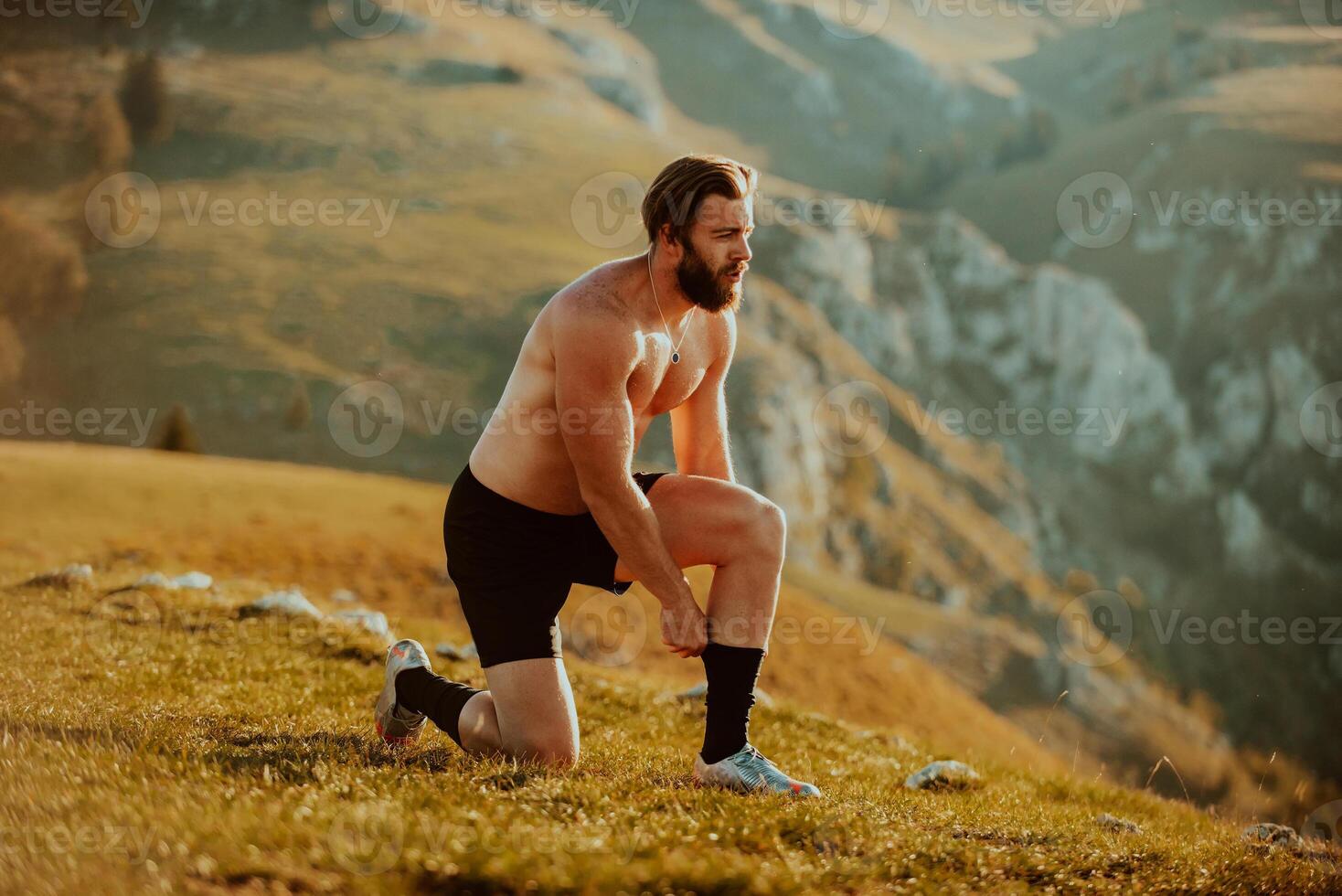 A determined athlete preparing for the start of training on the top of the mountain at sunrise. photo