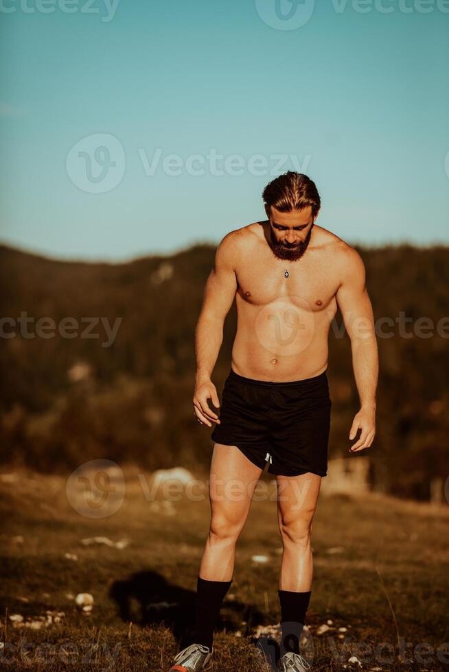 An athlete rests on top of a mountain after exhausting running training. photo