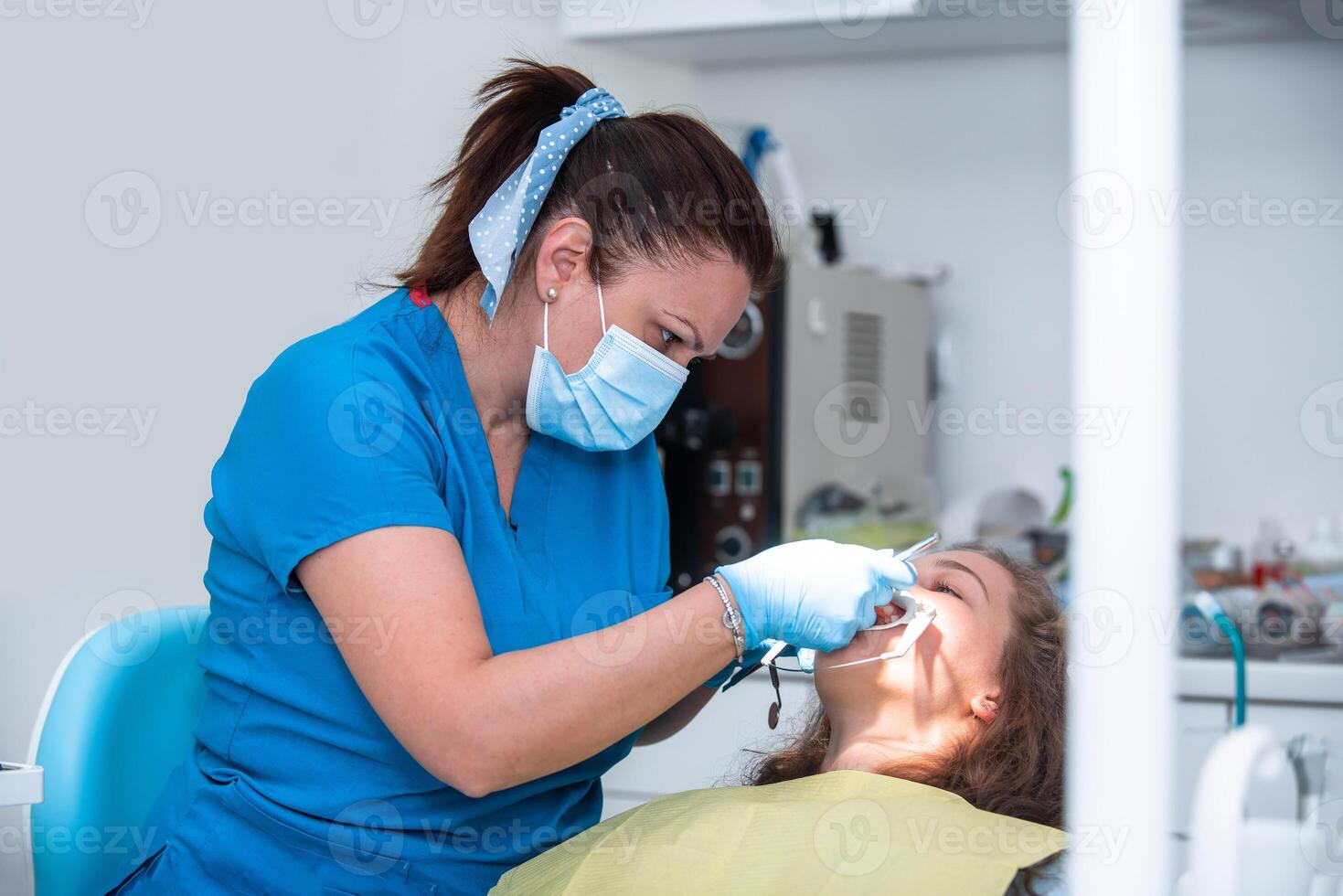 Dentist appointment at a dental clinic, placing braces locks on the teeth and pulling the archwire to fix it photo