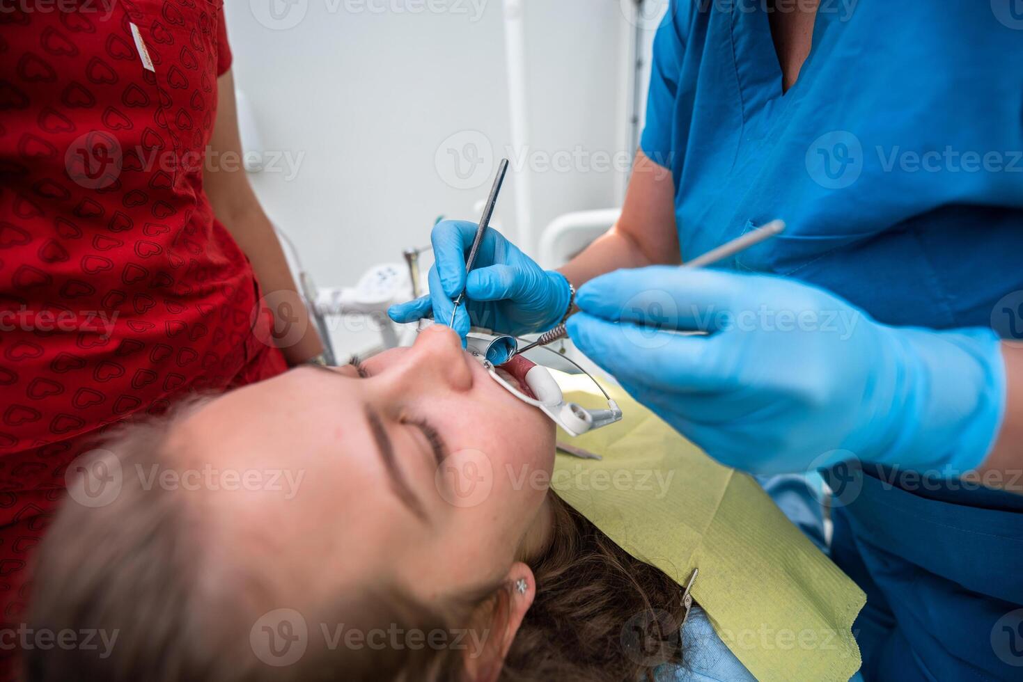 Dentist appointment at a dental clinic, placing braces locks on the teeth and pulling the archwire to fix it photo