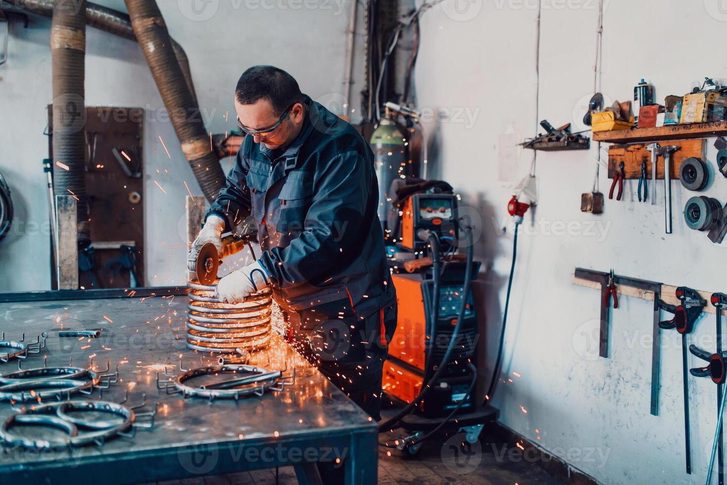 Locksmith in special clothes and goggles works in production. Metal processing with angle grinder. Sparks in metalworking. photo