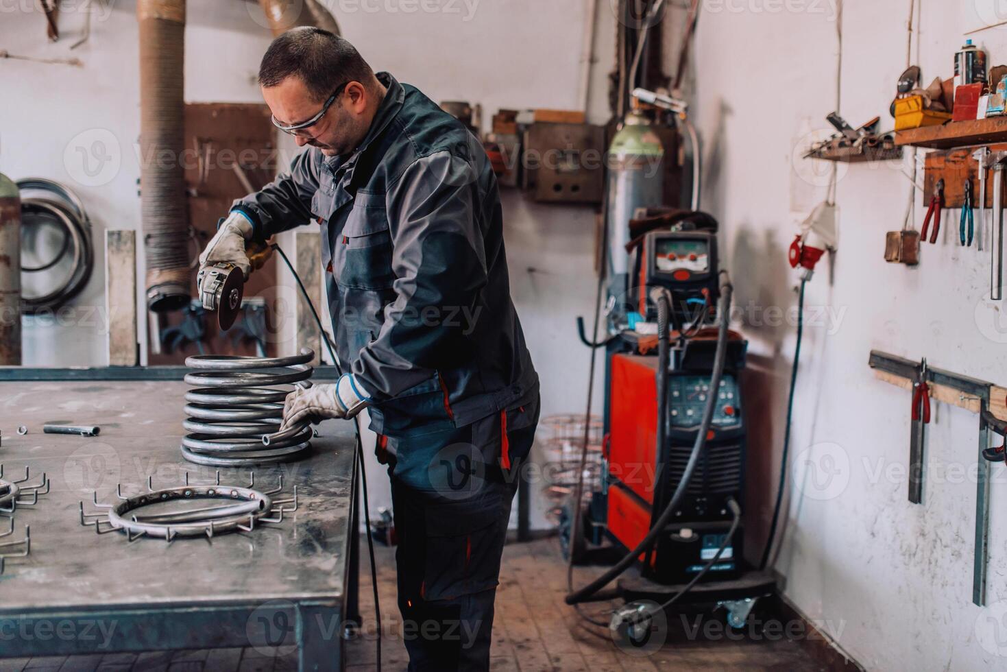 Locksmith in special clothes and goggles works in production. Metal processing with angle grinder. Sparks in metalworking. photo