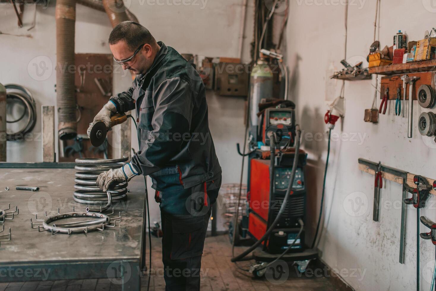 Locksmith in special clothes and goggles works in production. Metal processing with angle grinder. Sparks in metalworking. photo