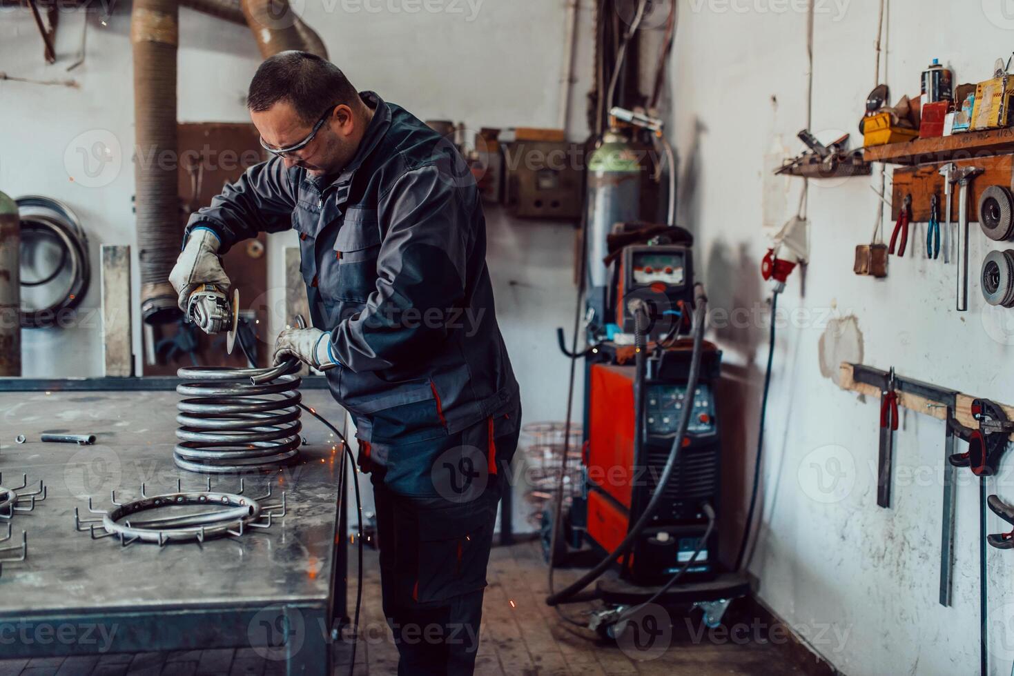 Locksmith in special clothes and goggles works in production. Metal processing with angle grinder. Sparks in metalworking. photo