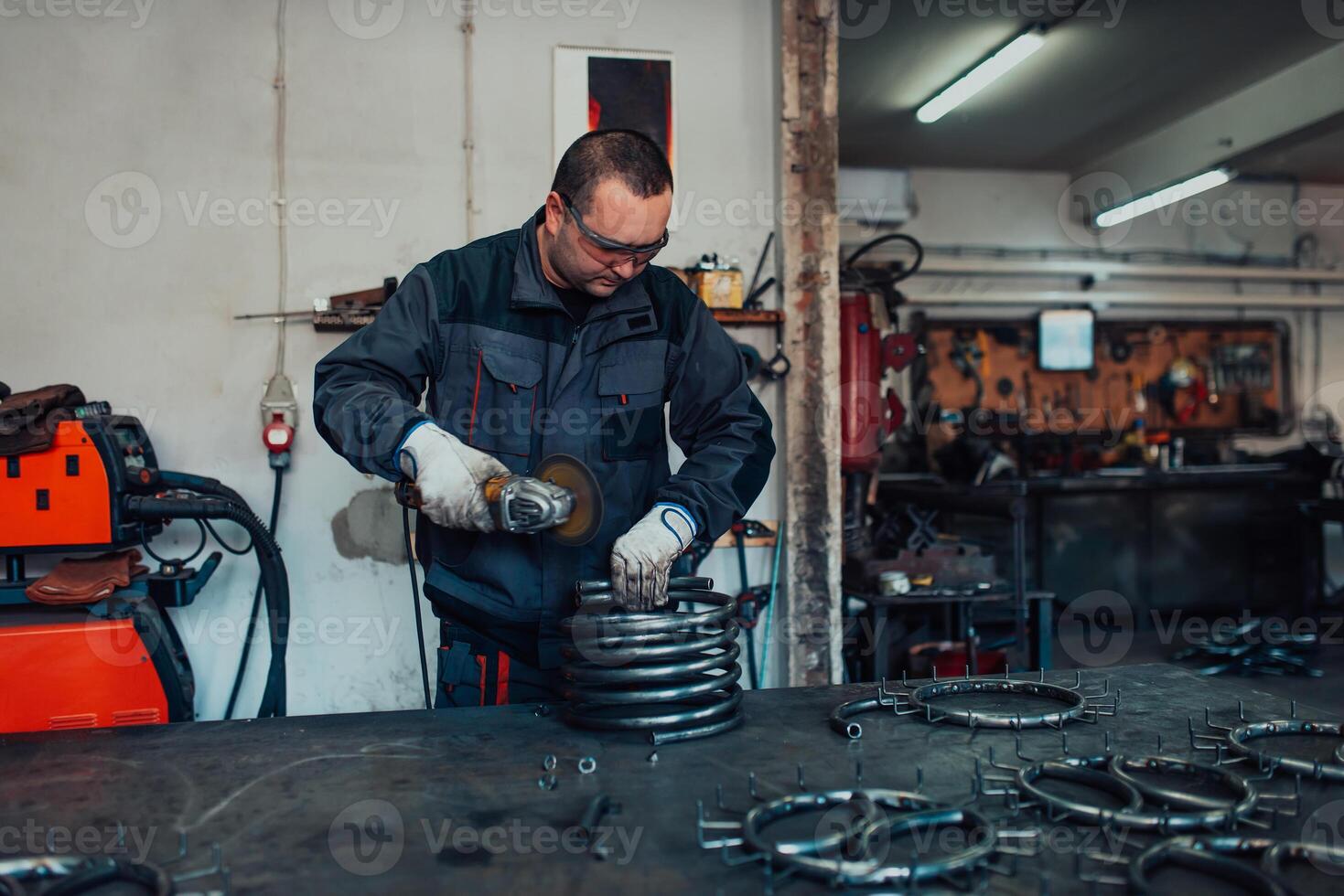Locksmith in special clothes and goggles works in production. Metal processing with angle grinder. Sparks in metalworking. photo