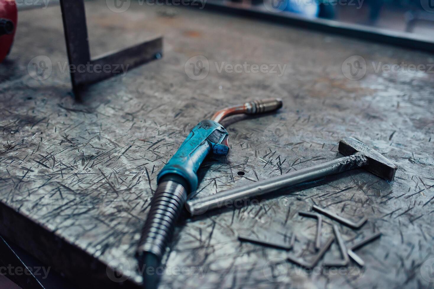 A hammer and a modern welding machine on a steel industrial table photo