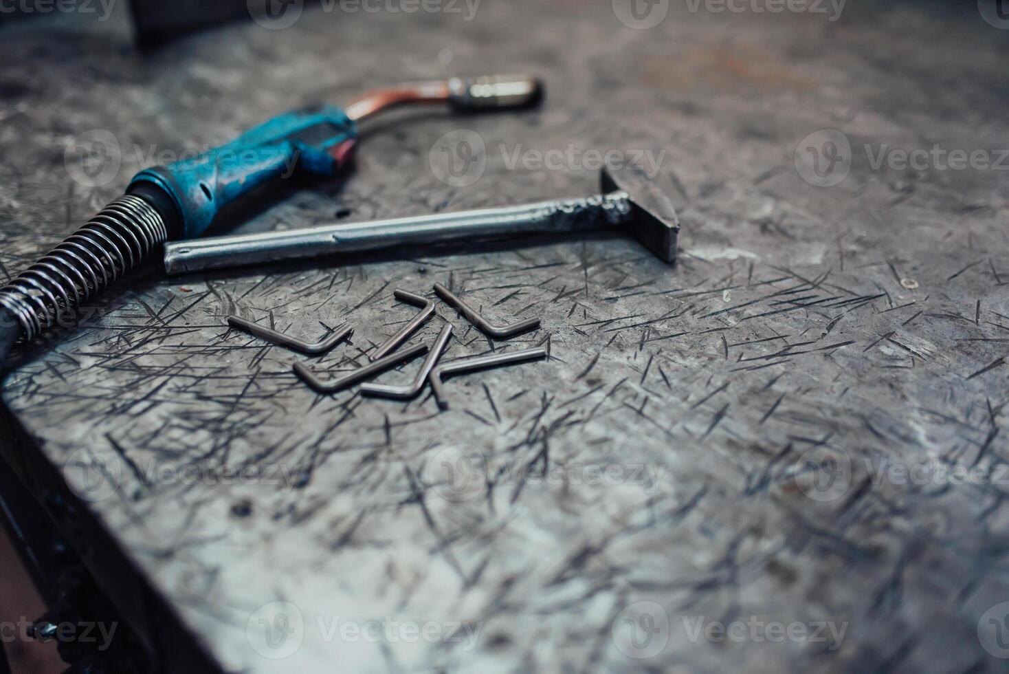 A hammer and a modern welding machine on a steel industrial table photo
