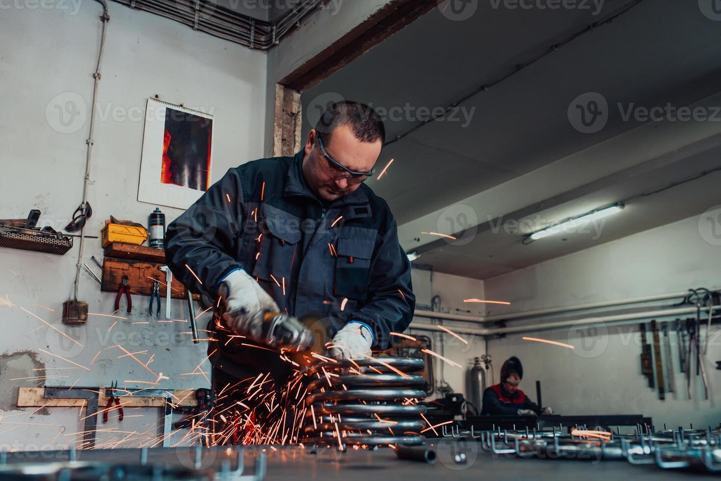 Locksmith in special clothes and goggles works in production. Metal processing with angle grinder. Sparks in metalworking. photo