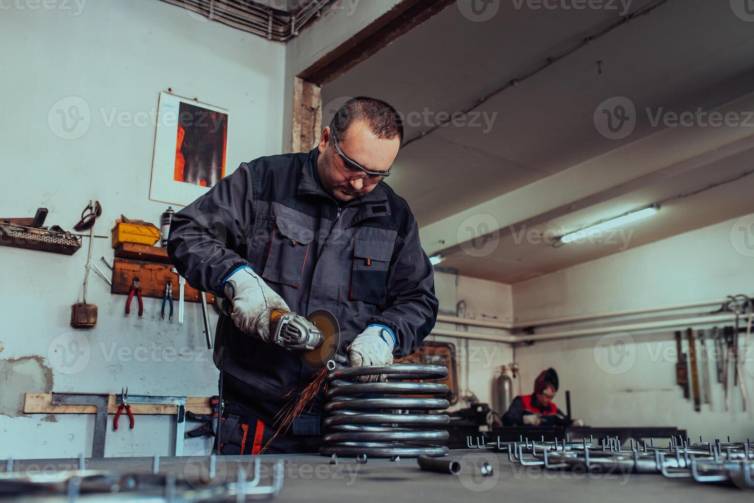 Locksmith in special clothes and goggles works in production. Metal processing with angle grinder. Sparks in metalworking. photo