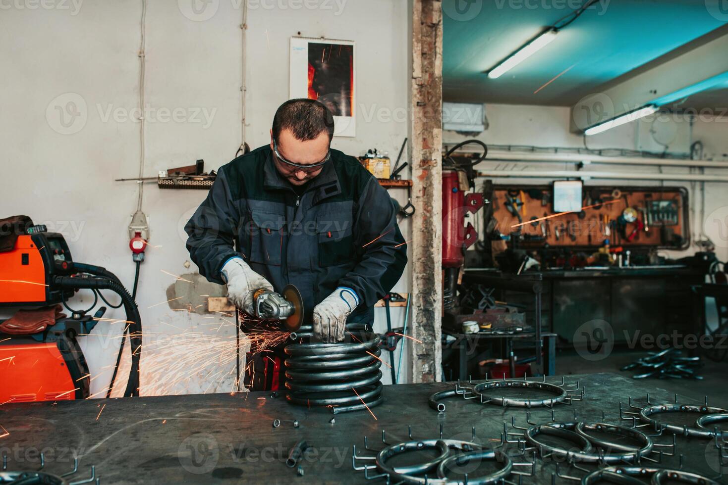 Locksmith in special clothes and goggles works in production. Metal processing with angle grinder. Sparks in metalworking. photo