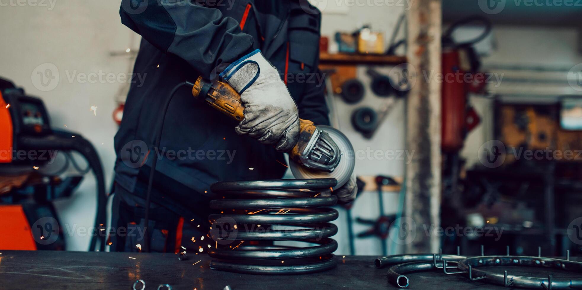 Locksmith in special clothes and goggles works in production. Metal processing with angle grinder. Sparks in metalworking. photo