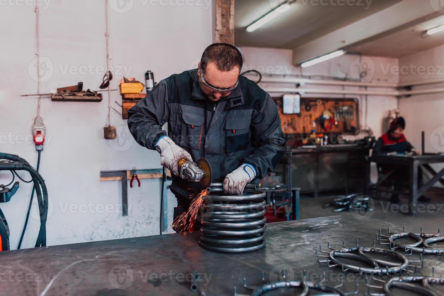 Locksmith in special clothes and goggles works in production. Metal processing with angle grinder. Sparks in metalworking. photo