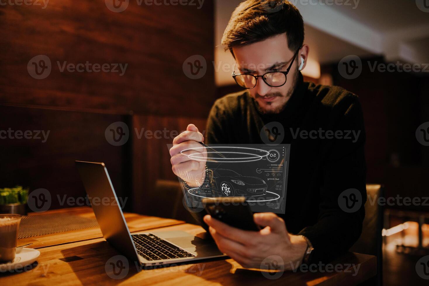 An engineer using a smarpthone in a cafe while viewing a hologram of the automotive industry. HUD of the automotive industry photo