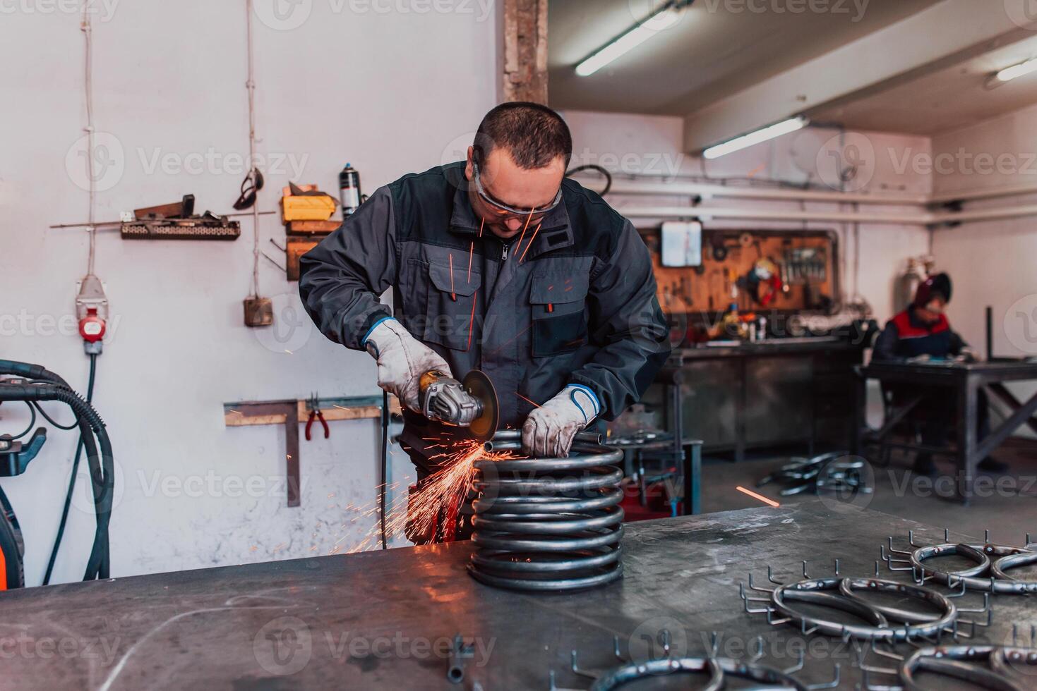 Locksmith in special clothes and goggles works in production. Metal processing with angle grinder. Sparks in metalworking. photo